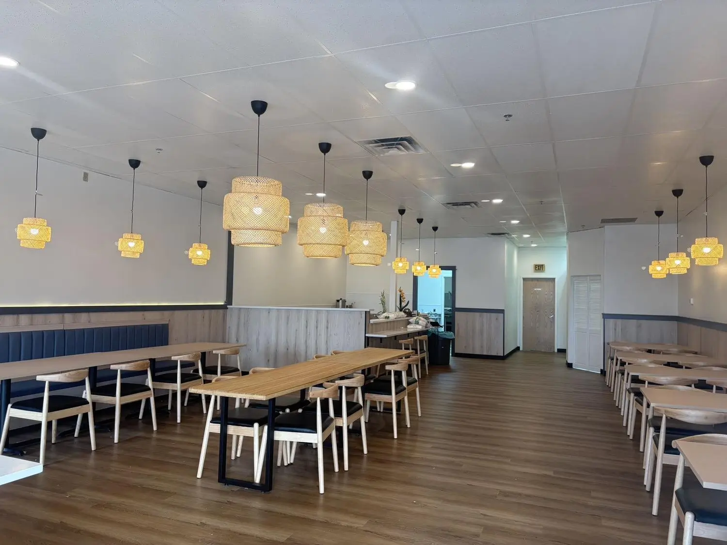 Spacious dining area with long tables, booths and woven pendant lights at Umai, a Asian Fusion Restaurant in Keizer